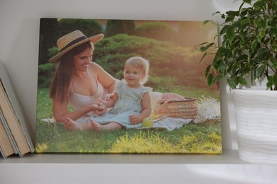 Photo of Canvas with printed photo of happy mother and her little daughter on shelf indoors