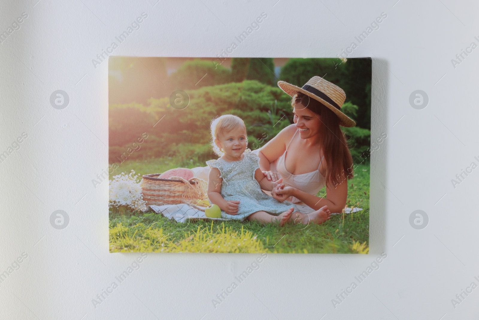 Photo of Canvas with printed photo of happy mother and her little daughter on white wall indoors