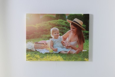 Photo of Canvas with printed photo of happy mother and her little daughter on white wall indoors