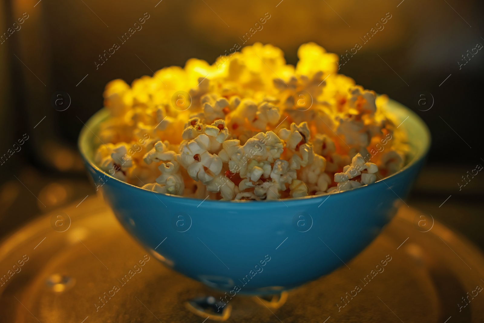 Photo of Bowl of tasty popcorn in microwave oven, closeup