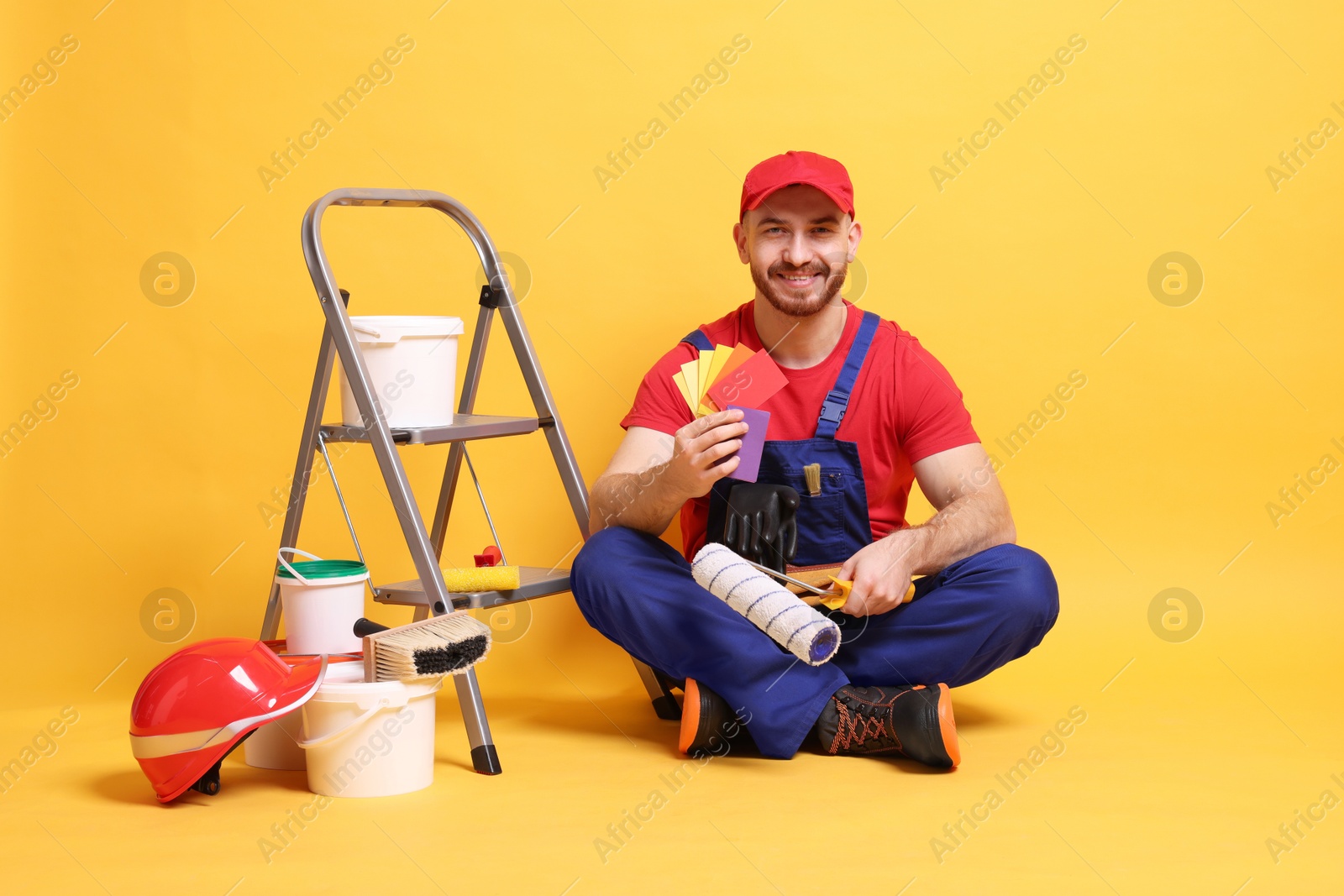 Photo of Professional painter with tools and supplies on orange background