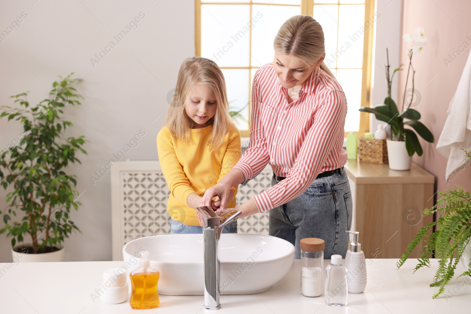 Photo of Mother and daughter washing their hands in bathroom