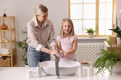 Photo of Happy mother and daughter washing their hands in bathroom