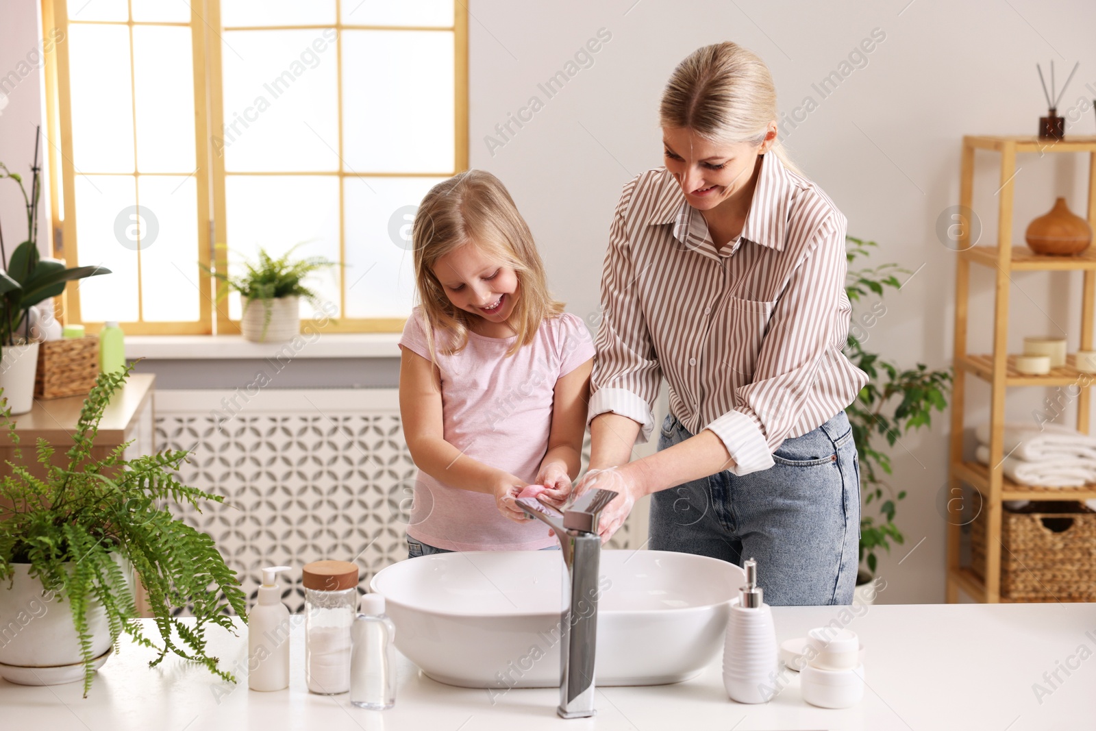 Photo of Happy mother and daughter washing their hands in bathroom