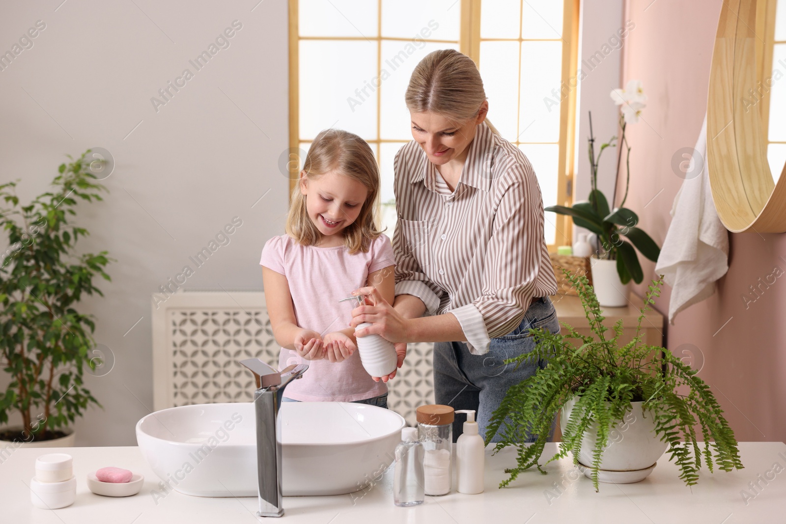 Photo of Happy mother and daughter washing their hands in bathroom