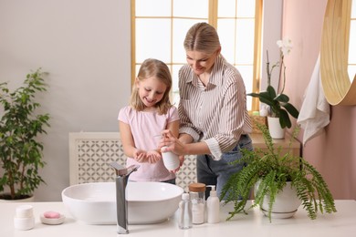 Photo of Happy mother and daughter washing their hands in bathroom