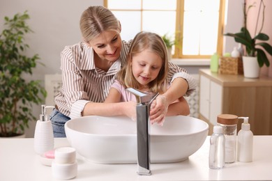 Photo of Happy mother and daughter washing their hands in bathroom