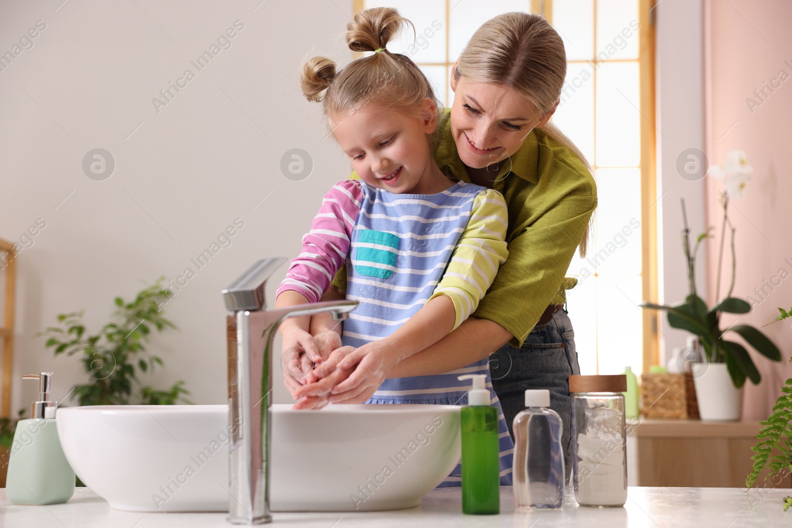 Photo of Happy mother and daughter washing their hands in bathroom