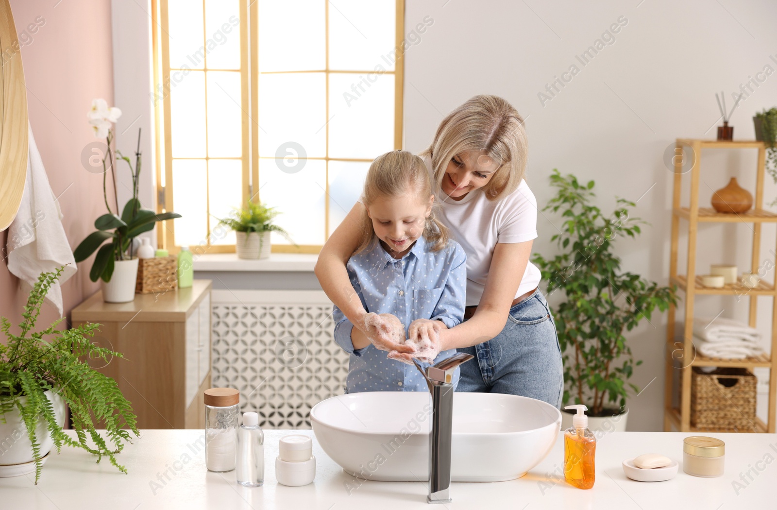 Photo of Happy mother and daughter washing their hands in bathroom