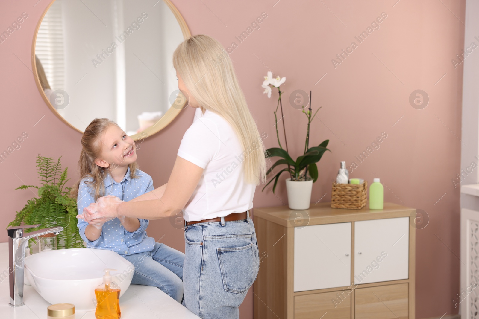 Photo of Happy daughter and mother washing their hands in bathroom