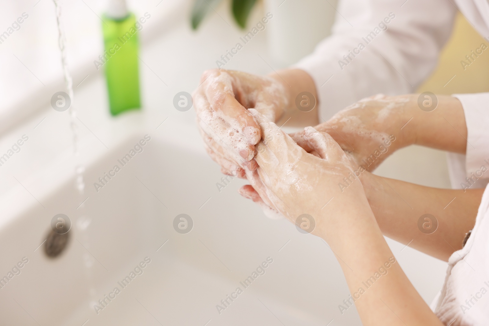 Photo of Mother and daughter washing their hands indoors, closeup. Space for text