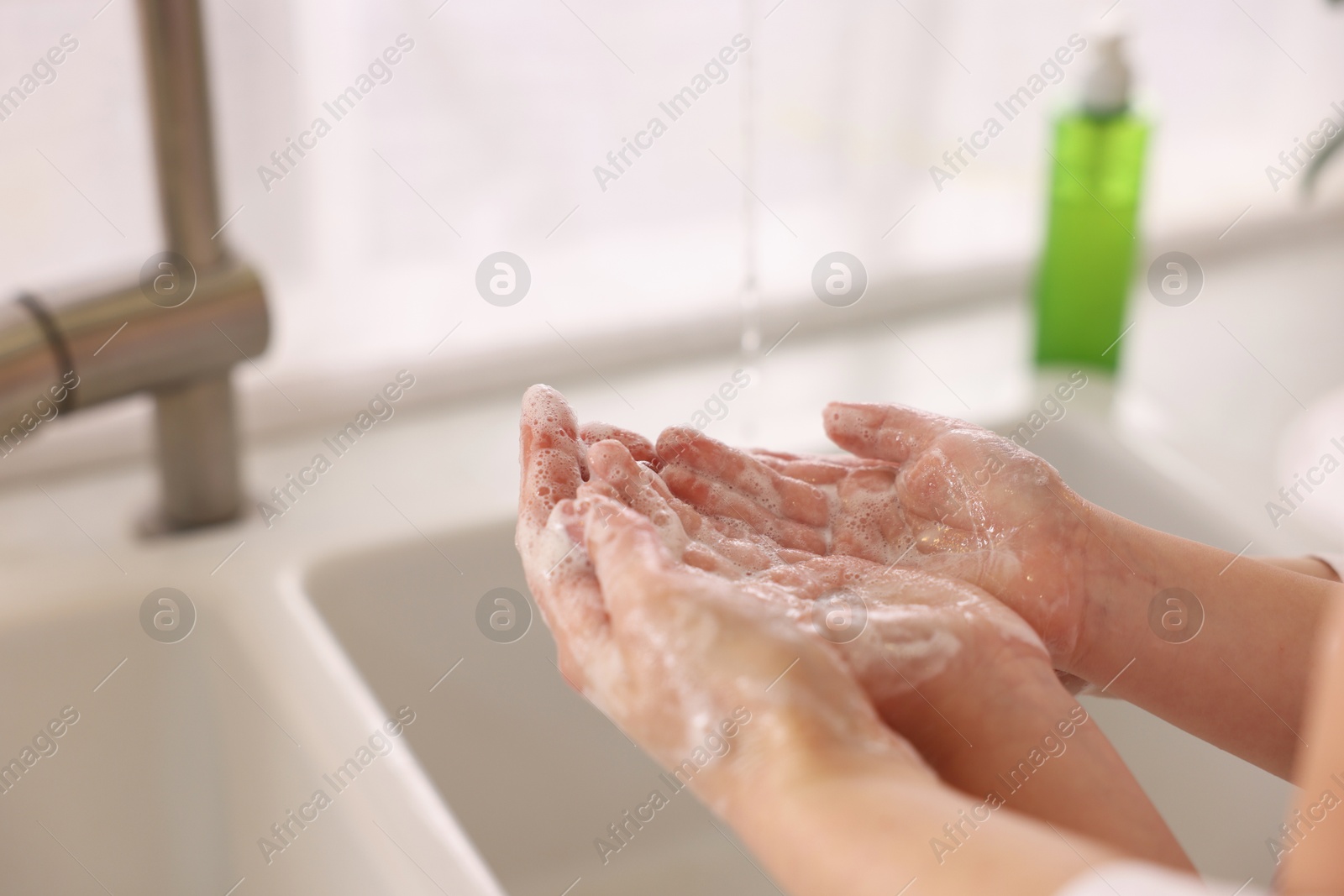 Photo of Mother and daughter washing their hands indoors, closeup. Space for text