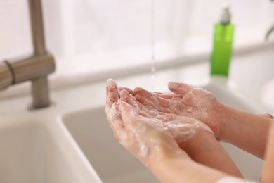 Photo of Mother and daughter washing their hands indoors, closeup. Space for text