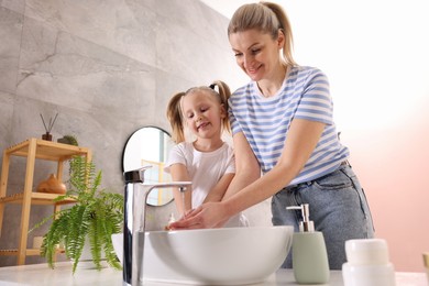 Photo of Happy mother and daughter washing their hands in bathroom, low angle view