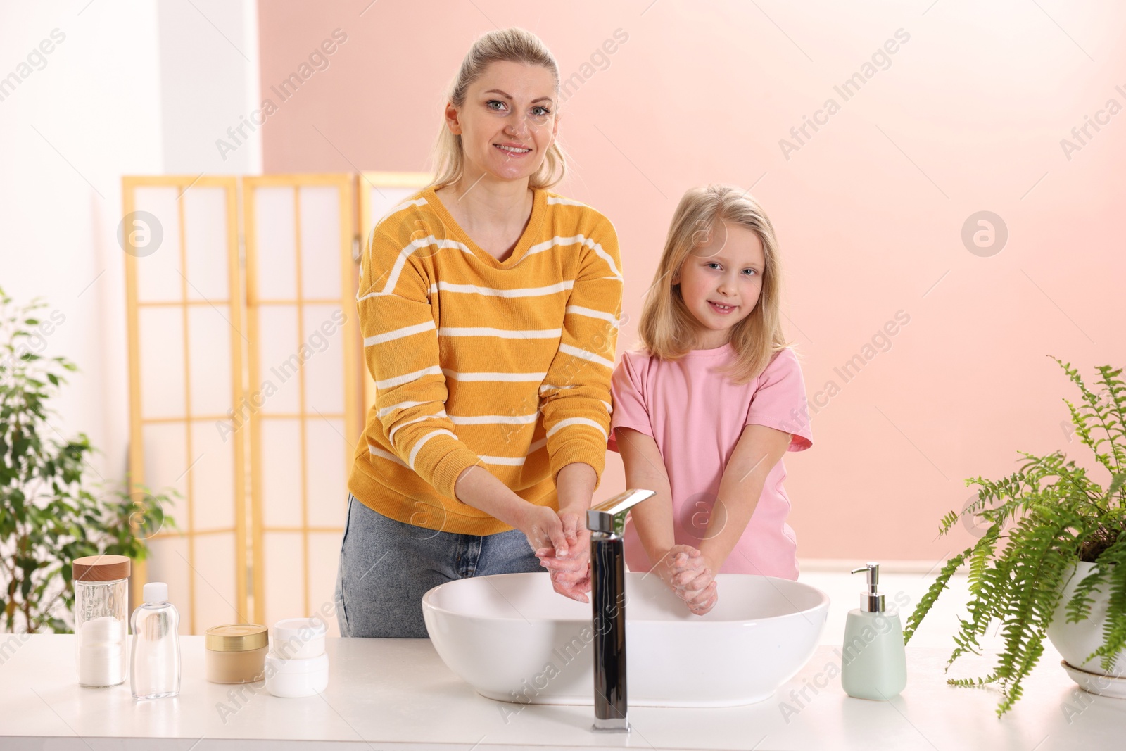 Photo of Happy mother and daughter washing their hands at home