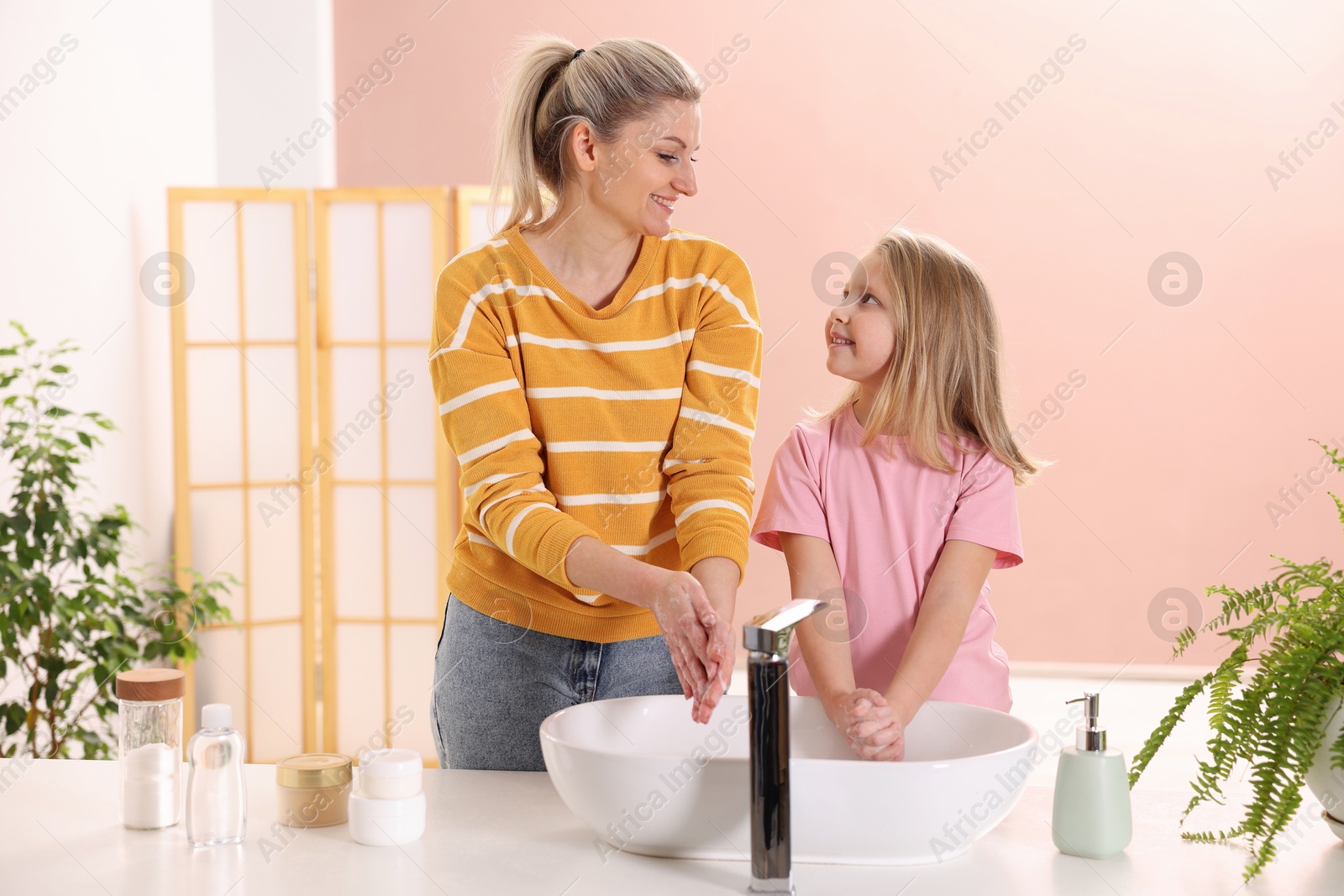 Photo of Happy mother and daughter washing their hands at home