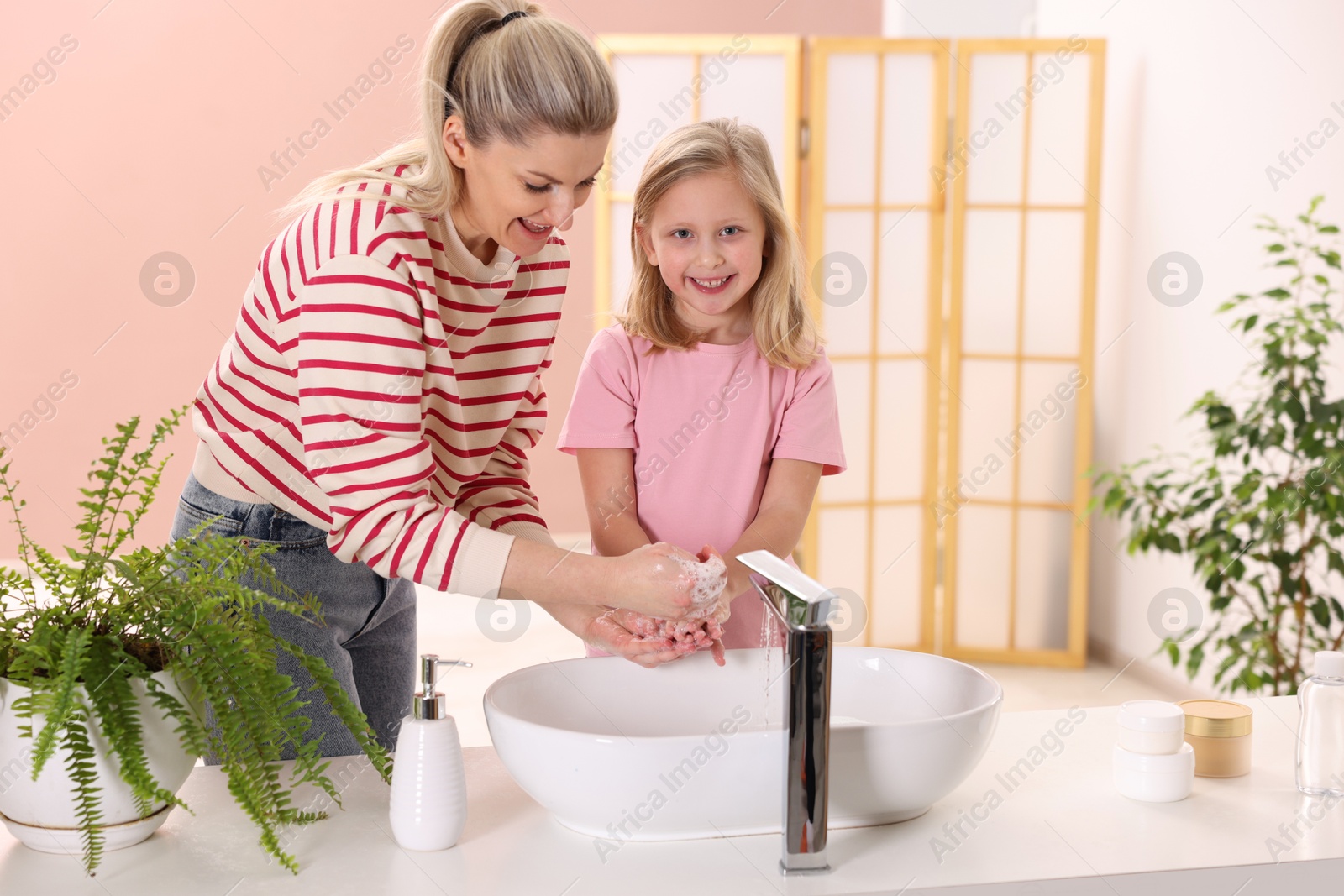 Photo of Happy mother and daughter washing their hands at home