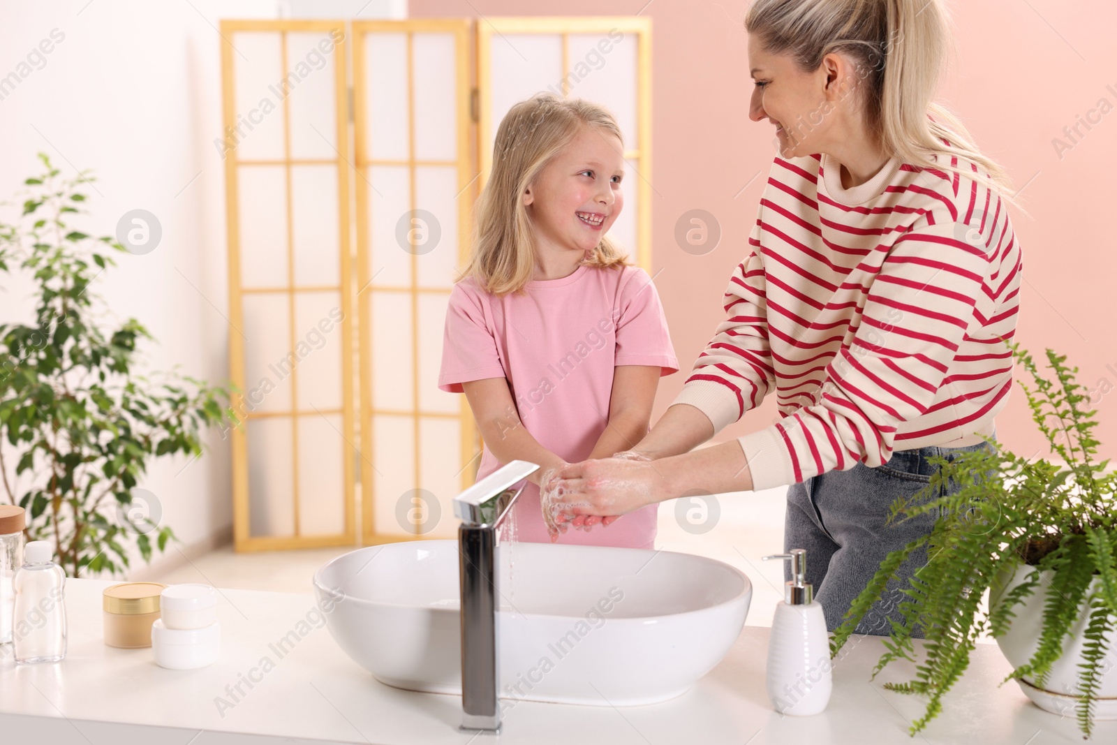 Photo of Happy mother and daughter washing their hands at home. Space for text