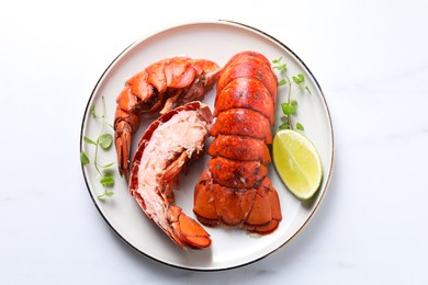 Delicious tails of boiled lobsters served on white table, top view