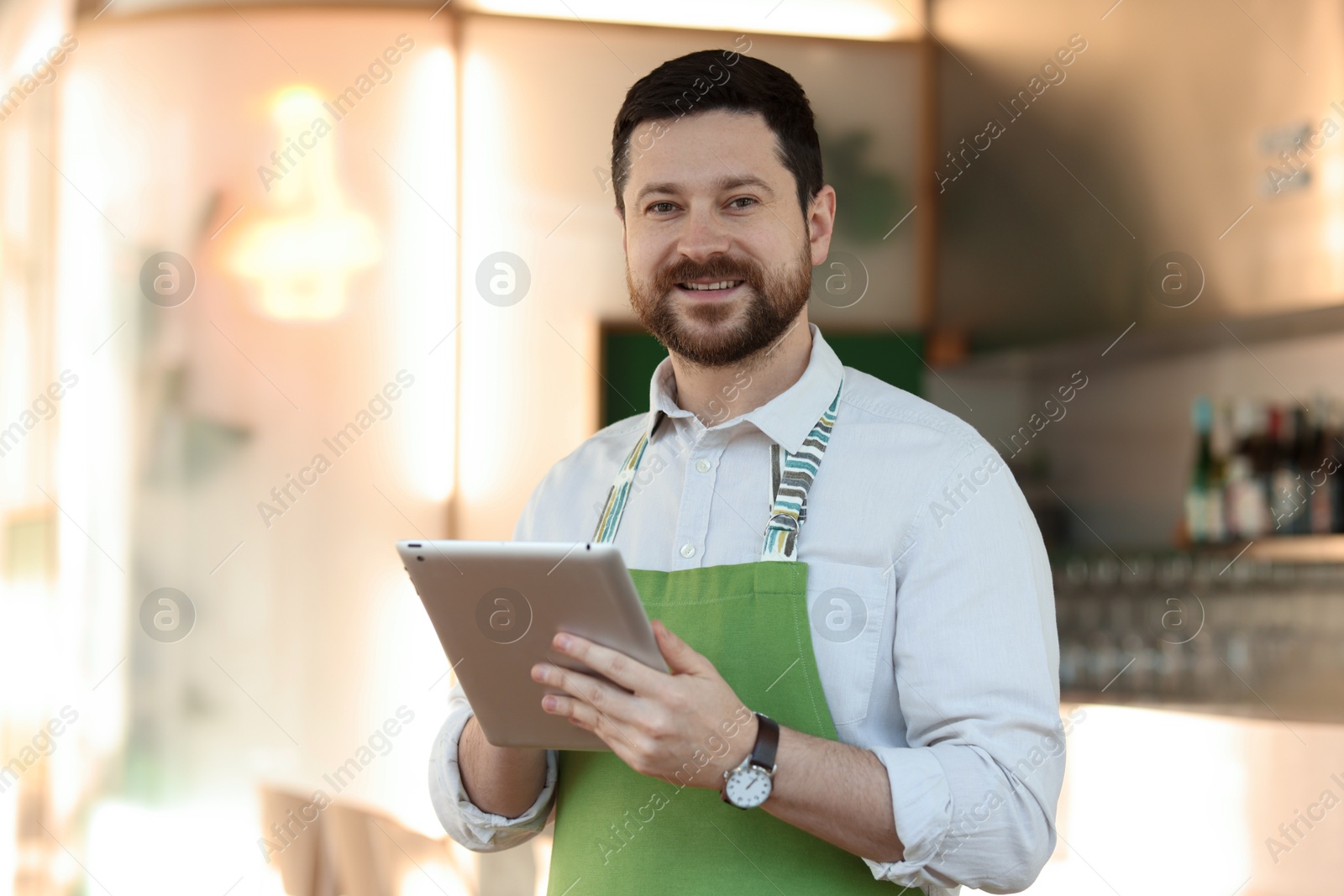 Photo of Portrait of smiling business owner with tablet in his cafe