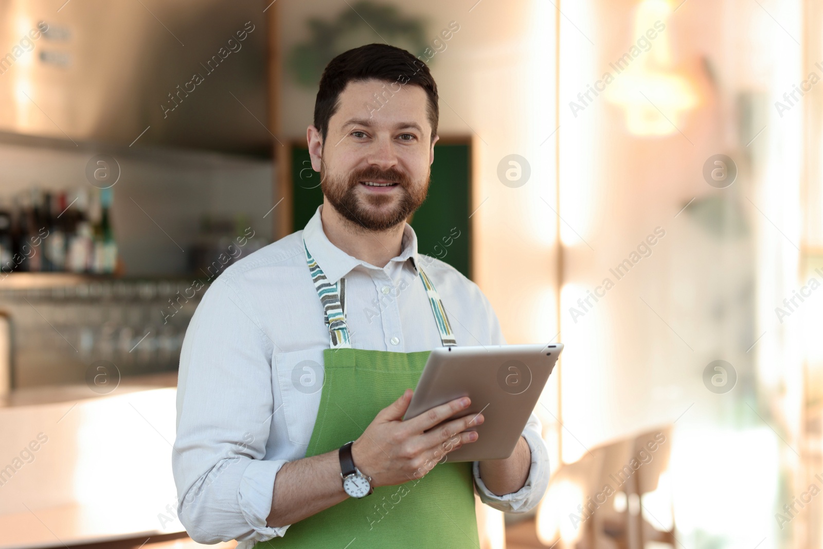 Photo of Smiling business owner with tablet in his cafe