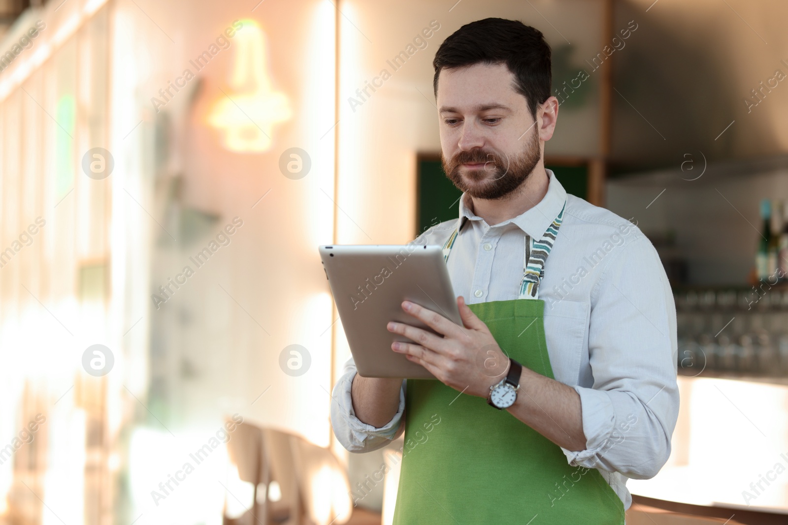 Photo of Handsome business owner working with tablet in his cafe. Space for text