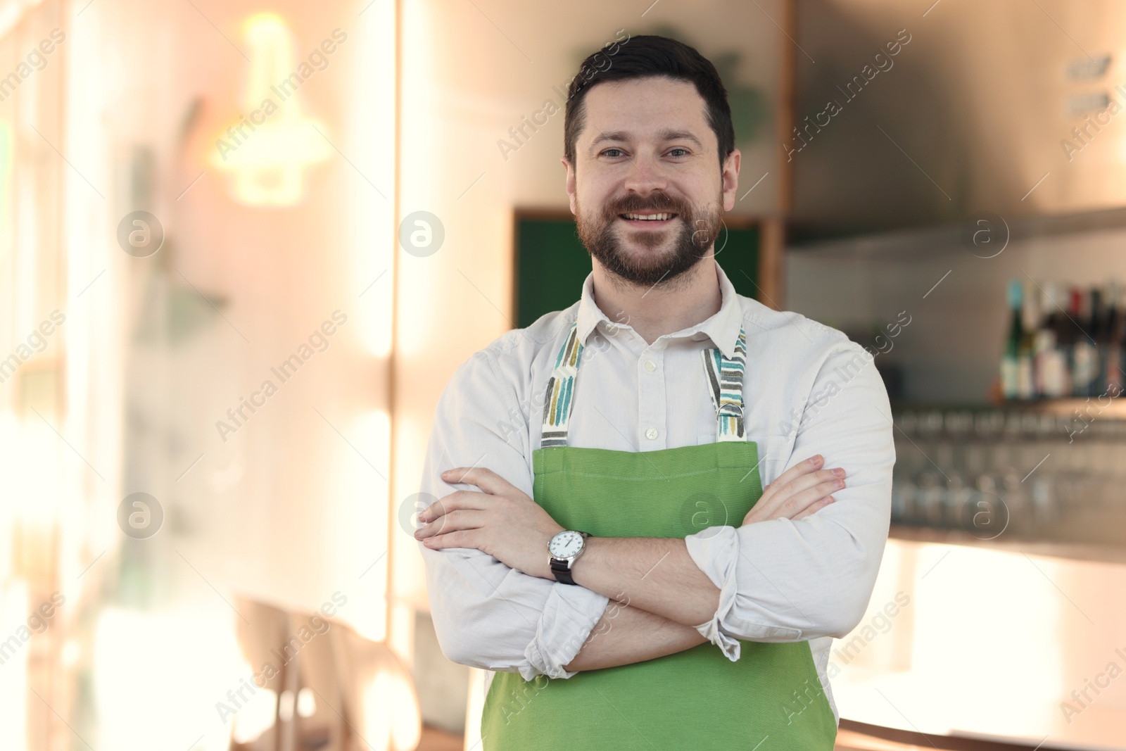 Photo of Portrait of smiling business owner with crossed arms in his cafe. Space for text