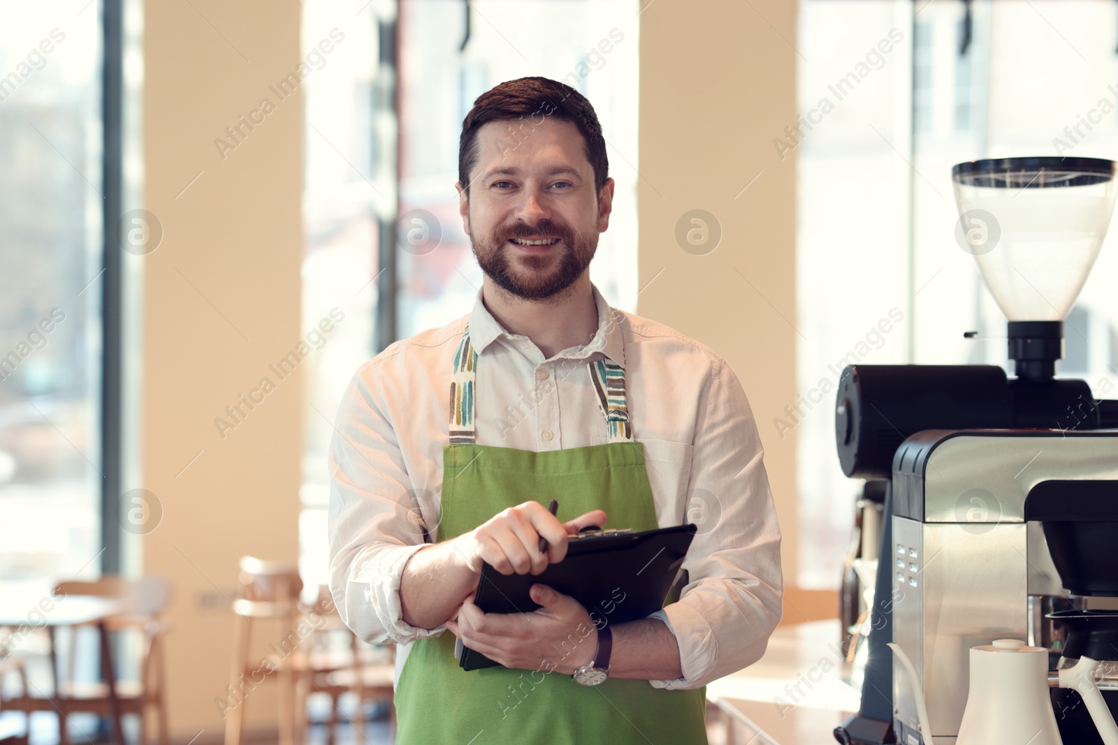 Photo of Smiling business owner working with clipboard in his cafe