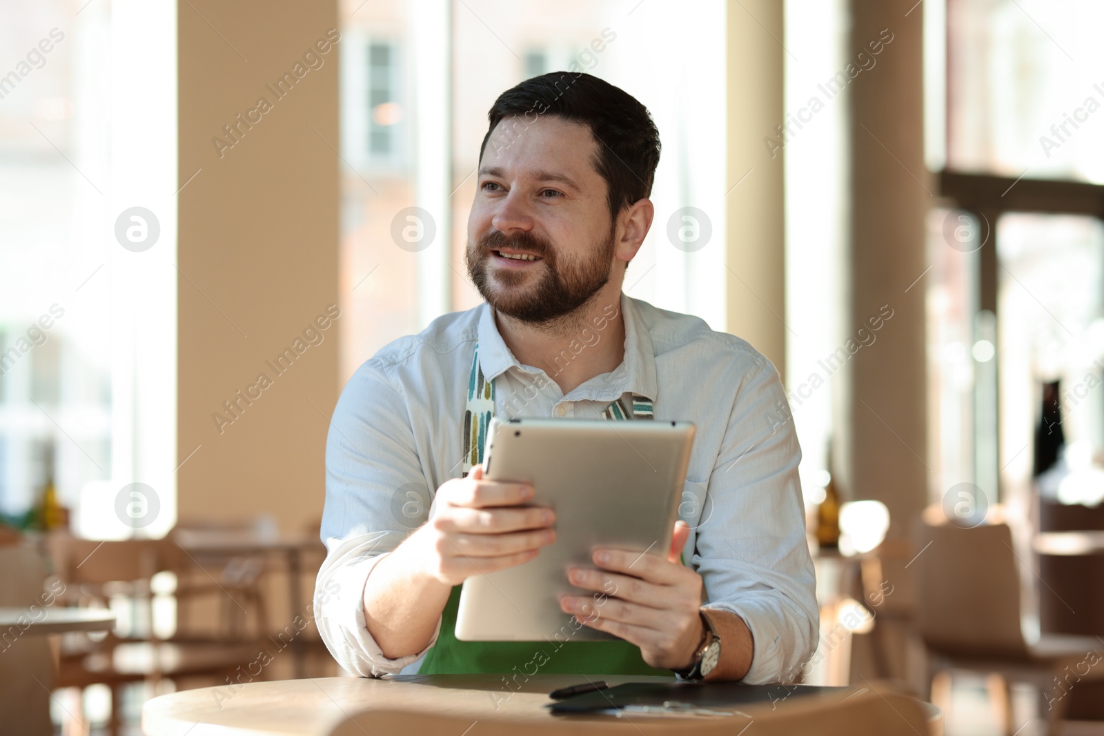 Photo of Smiling business owner with tablet in his cafe