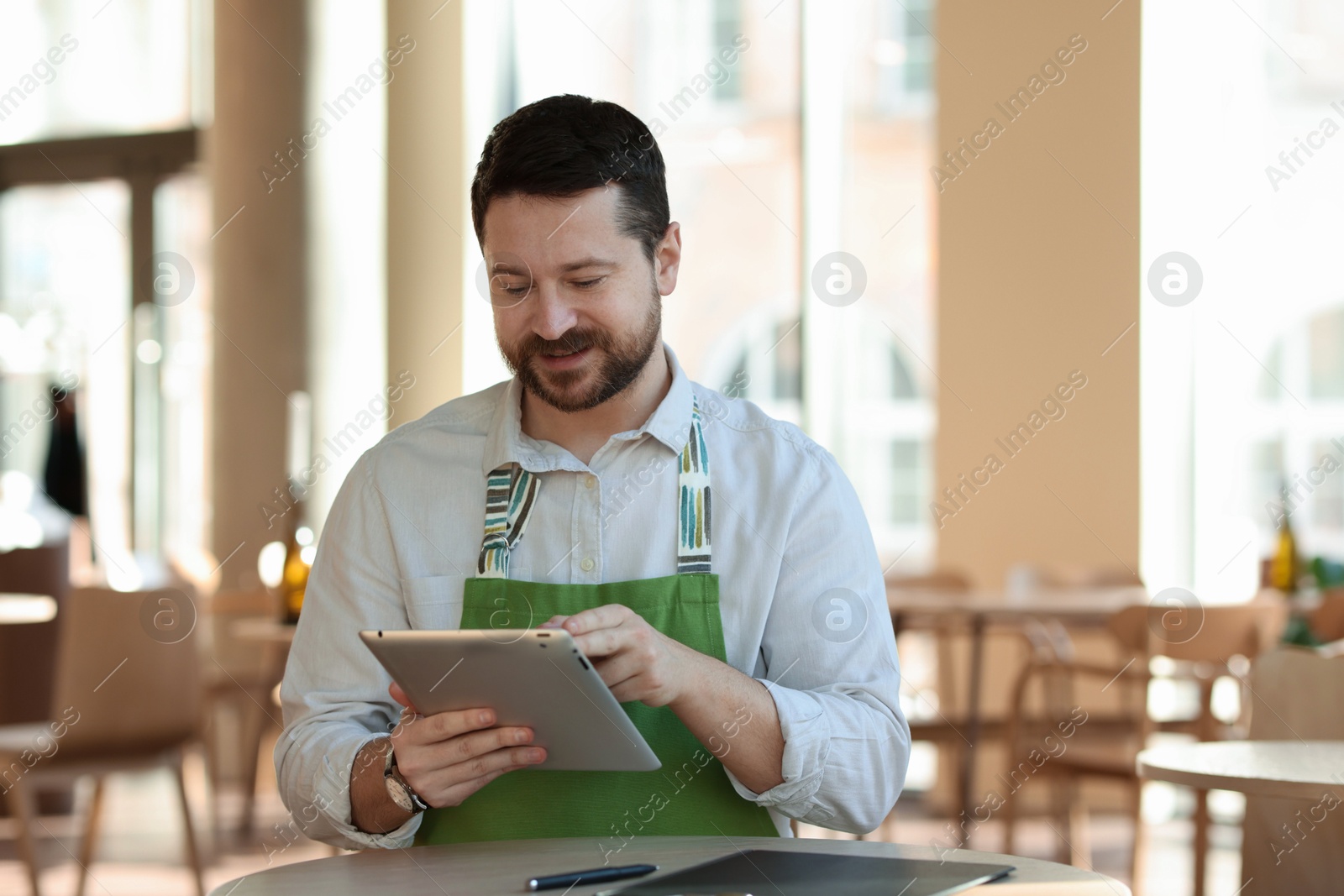 Photo of Handsome business owner working with tablet in his cafe