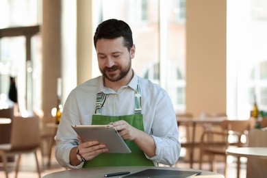 Handsome business owner working with tablet in his cafe