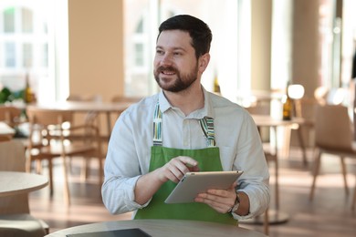 Photo of Smiling business owner with tablet in his cafe