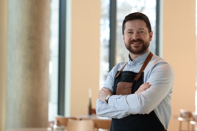 Photo of Portrait of smiling business owner with crossed arms in his cafe. Space for text