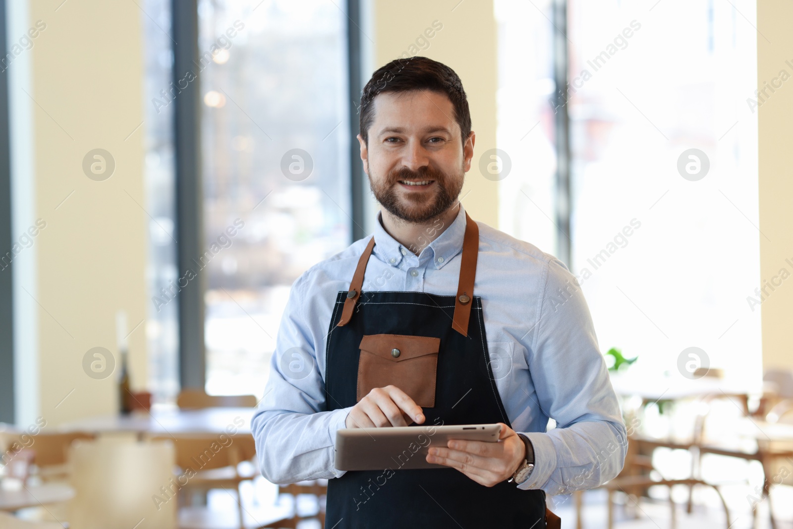 Photo of Portrait of smiling business owner with tablet in his cafe