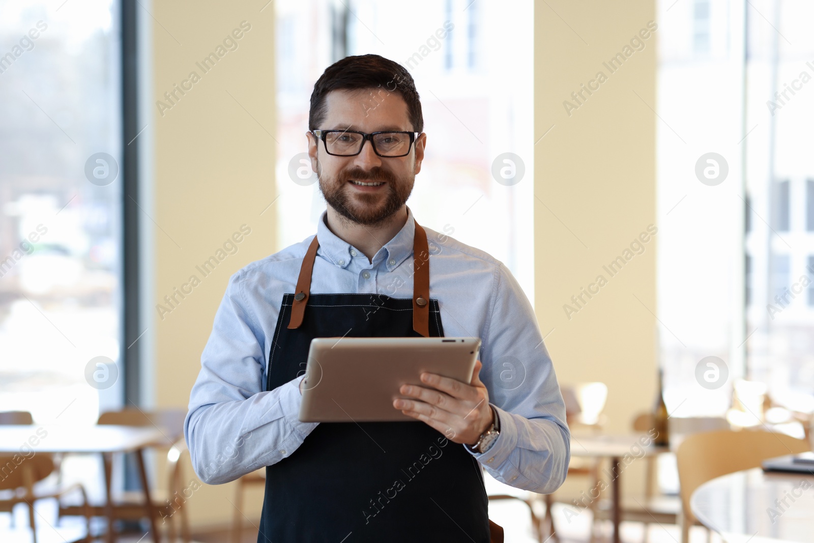 Photo of Portrait of smiling business owner with tablet in his cafe