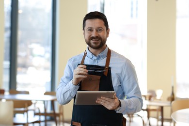 Photo of Portrait of smiling business owner with tablet in his cafe