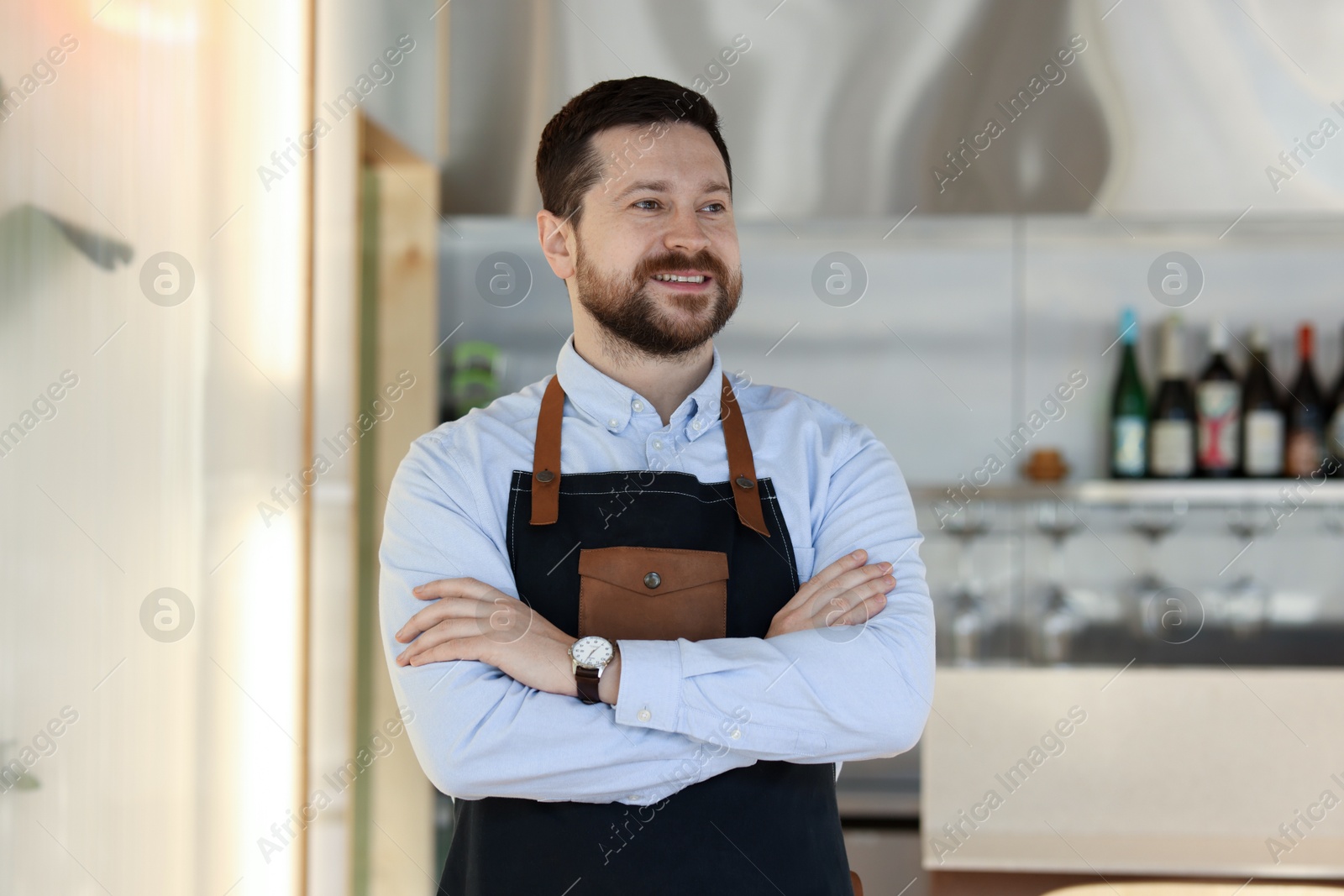 Photo of Smiling business owner with crossed arms in his cafe