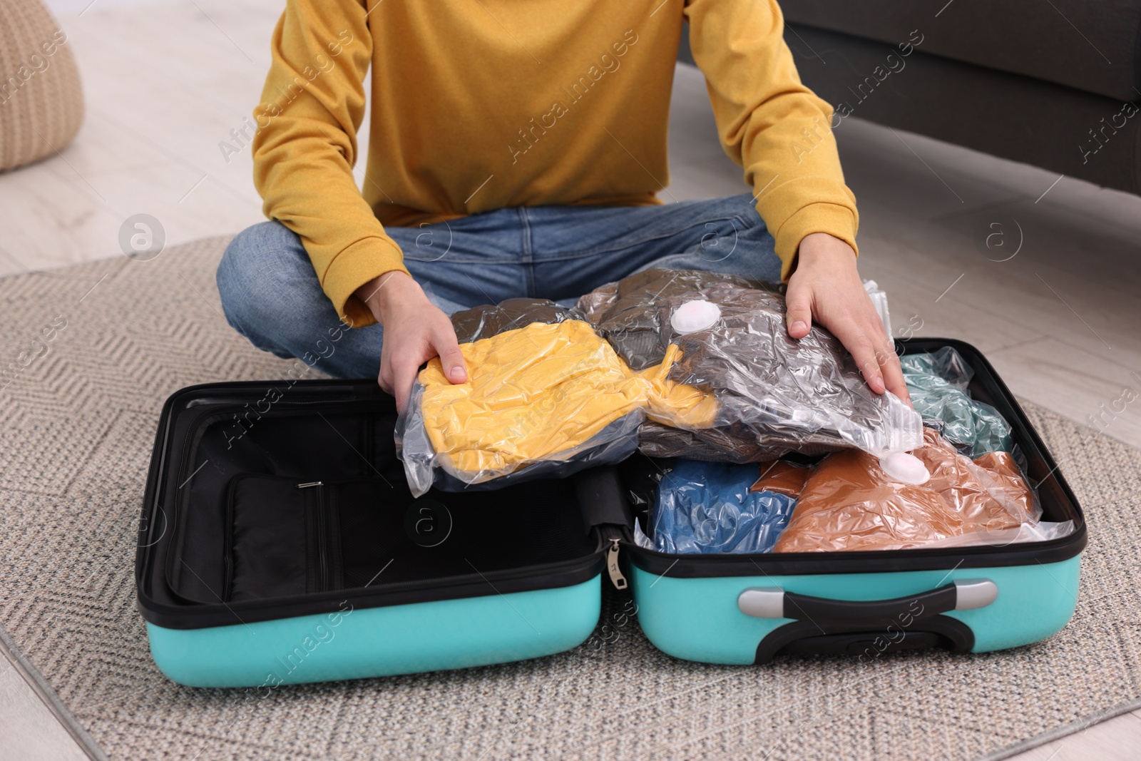 Photo of Man packing clothes into vacuum bag on floor indoors, closeup