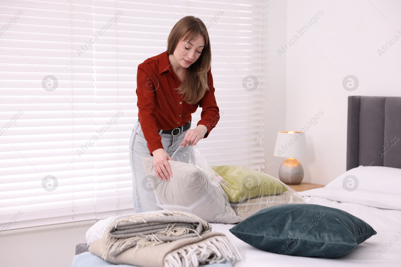 Photo of Woman packing pillows into vacuum bag at home