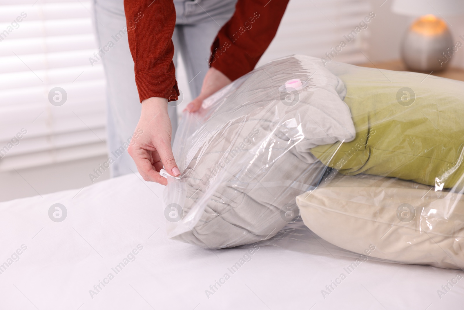 Photo of Woman packing pillows into vacuum bag at home, closeup