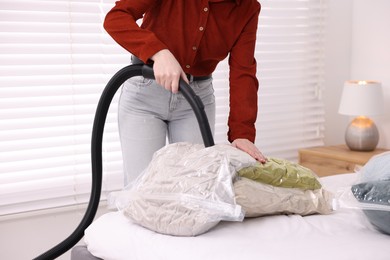 Photo of Woman sealing vacuum bag with pillows at home, closeup