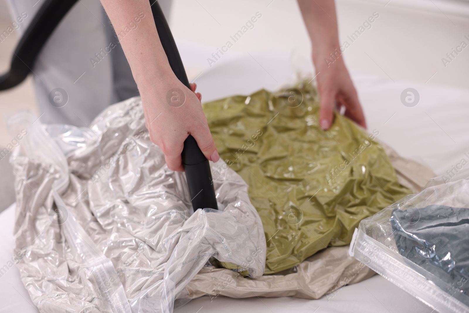 Photo of Woman sealing vacuum bag with pillows at home, closeup