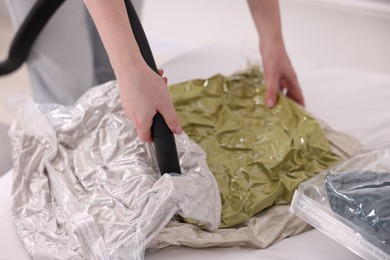 Photo of Woman sealing vacuum bag with pillows at home, closeup