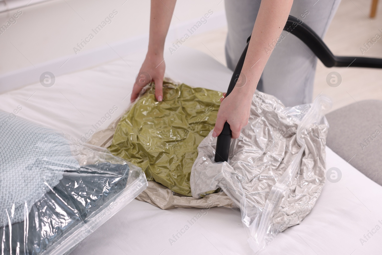 Photo of Woman sealing vacuum bag with pillows at home, closeup