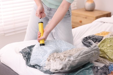 Photo of Woman sealing vacuum bag with blankets at home, closeup