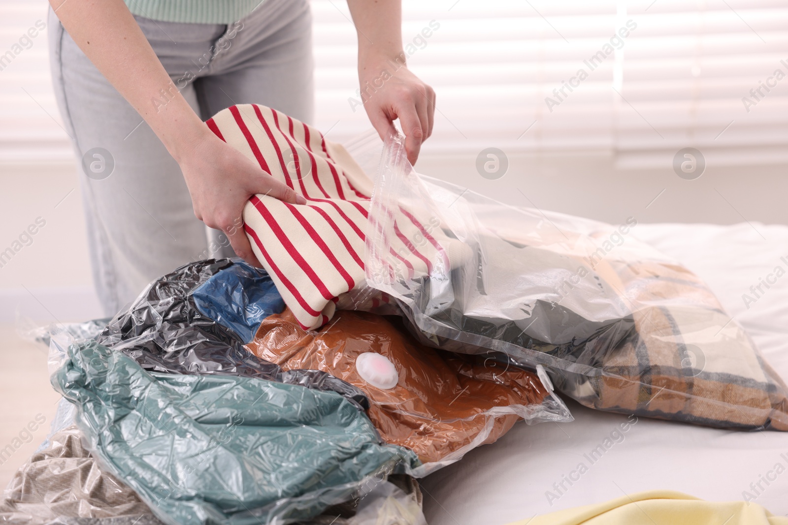 Photo of Woman packing clothes into vacuum bag at home, closeup