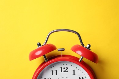 Photo of Red alarm clock on yellow background, top view