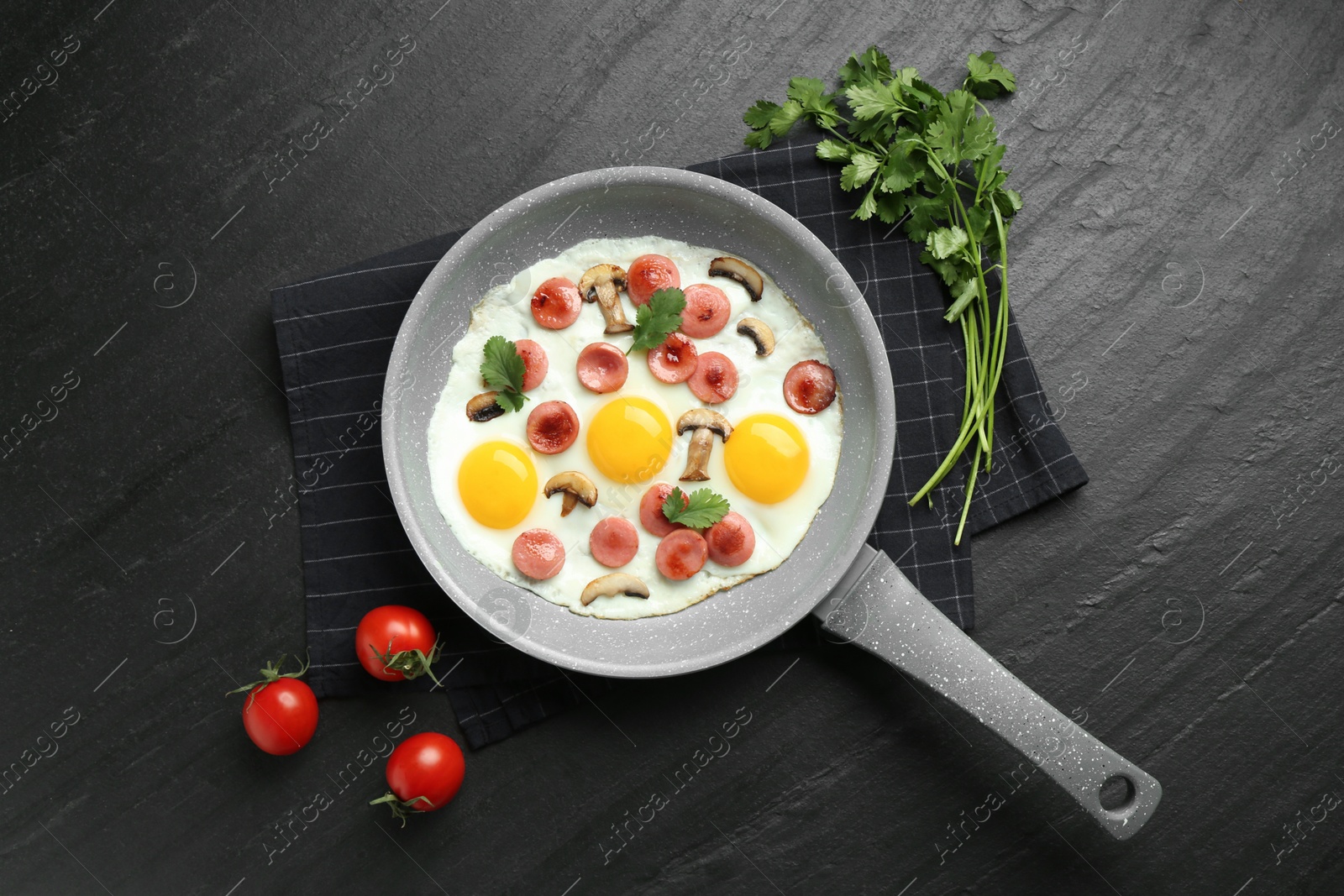 Photo of Tasty fried eggs with cut sausages and mushrooms served on black table, flat lay