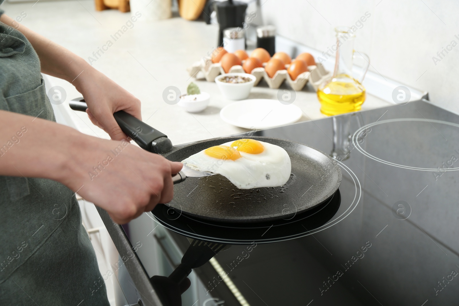 Photo of Woman taking fried eggs from frying pan in kitchen, closeup