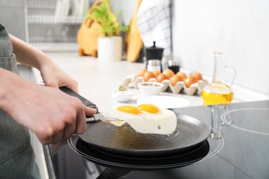 Photo of Woman taking fried eggs from frying pan in kitchen, closeup